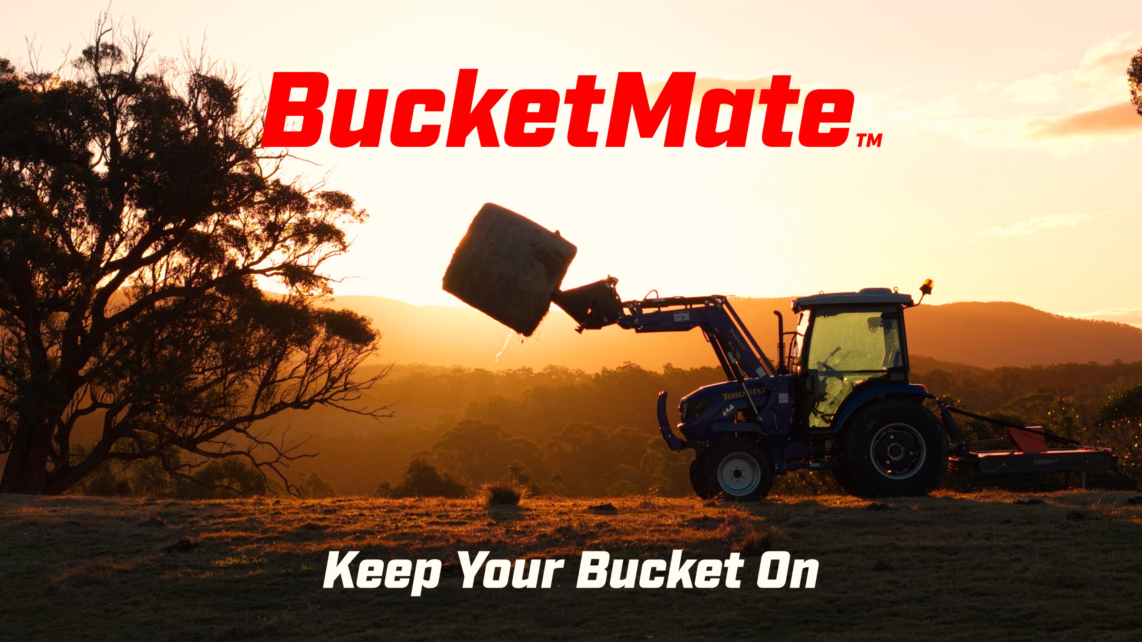 BucketMate in a 4-in-1 bucket with hay spear  forks attached, lifting a round hay bale